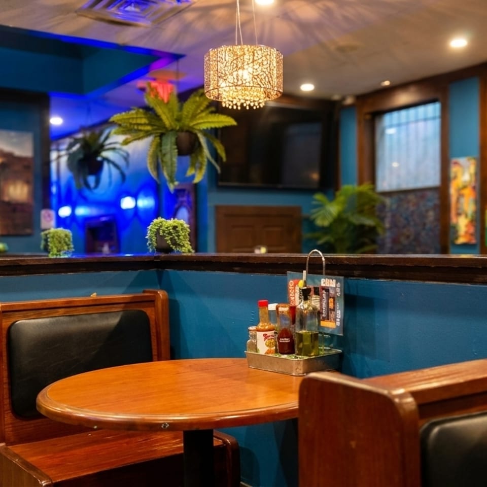 Cozy restaurant interior with blue walls, wooden booths, hanging plants, and a table with condiments.