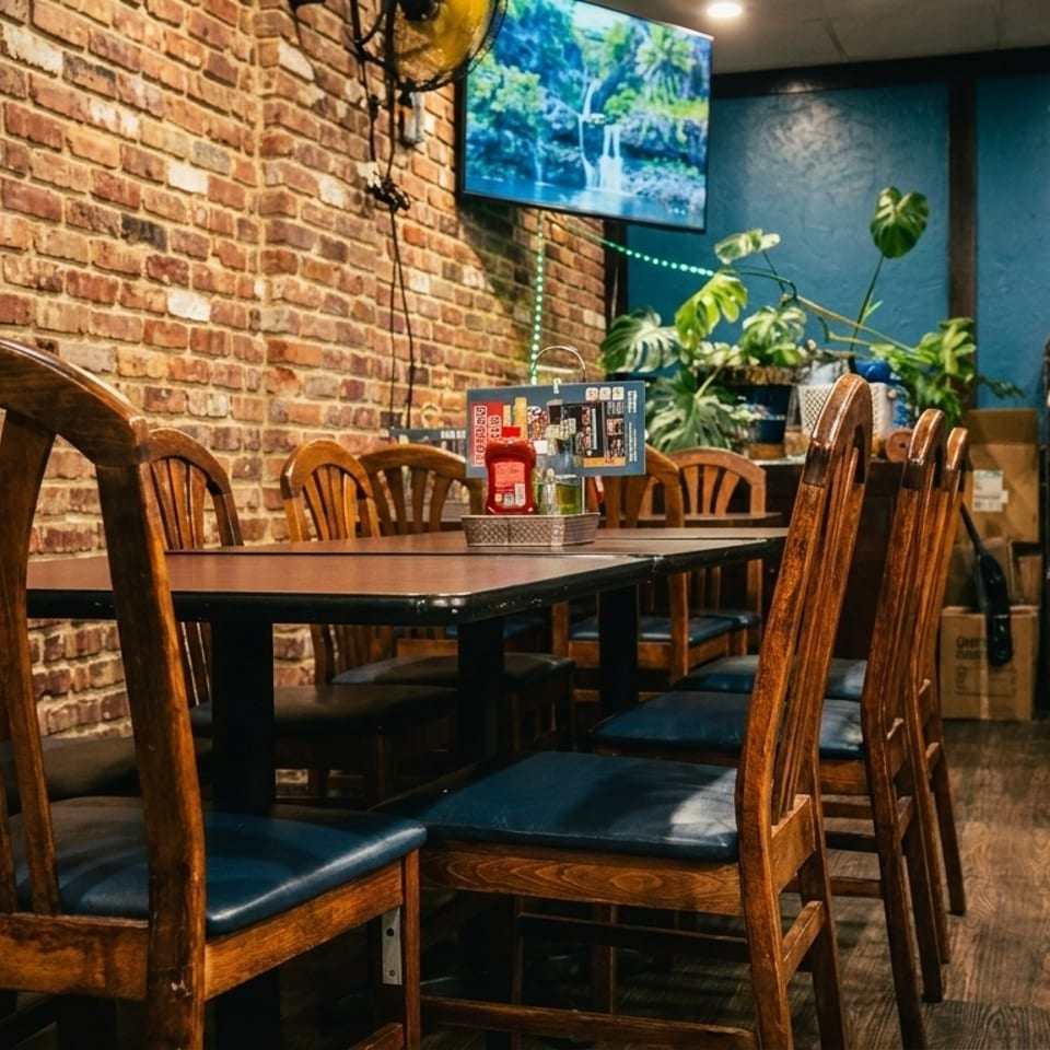 Restaurant interior with wooden chairs, brick wall, blue wall, and a TV displaying a waterfall.