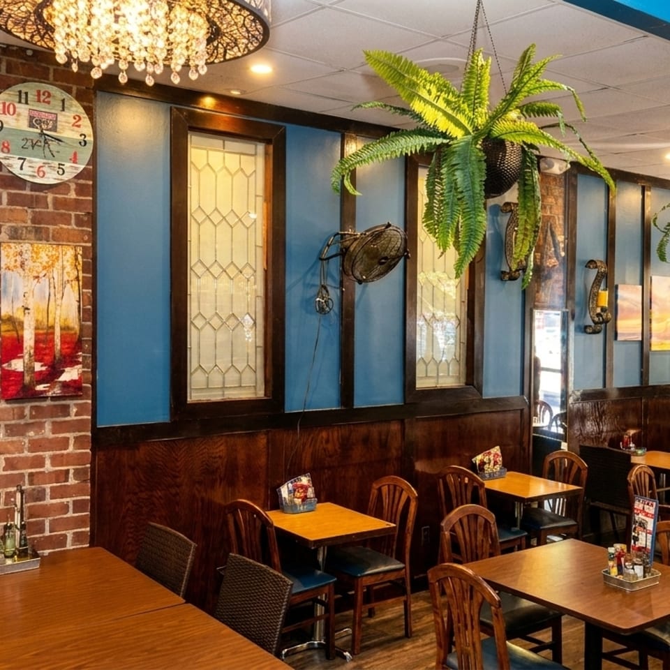 Cozy restaurant interior with brick walls, blue accents, wooden tables, and hanging plants.